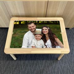 a family photo on a wooden table in the middle of a carpeted area with grey carpeting