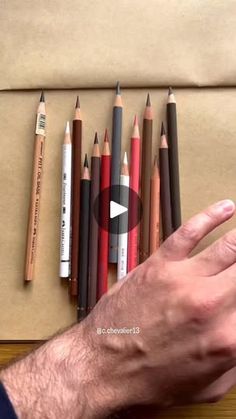 a man is holding his hand out in front of several pencils