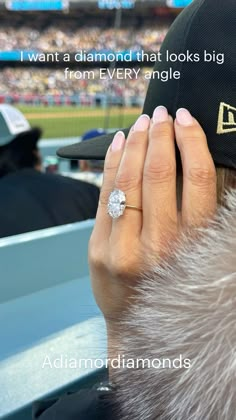 a woman's hand with a diamond ring on top of her finger at a baseball game