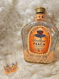 An eye catcher of a decor piece. This 750ml Crown Royal Peach empty bottle will be a perfect addition to your cabinet display. Can be used as a decanter or just to jazz up your cabinet.  This is a handmade item. Each stone was individually and personally placed. Make sure you examine the pictures as it is the actual item you will receive.  Bottle contains iridescent orange and silver rainbow rhinestones including the screw on top. It comes with a matching shot glass for a complete set. Each set Placemats From Crown Royal Bags, Crown Royal Bags Knomes, Glitter Crown Royal Bottle, Decorated Hennessy Bottle, Diy Liquor Bottle Crafts, Custom Liquor Bottles, Crown Royal Peach, Crown Royal Crafts, Alcohol Bottle Decorations