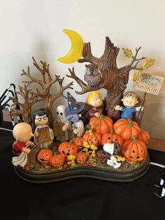 a group of halloween figurines sitting on top of a table next to a tree