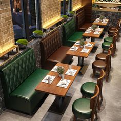 an empty restaurant with green booths and wooden tables