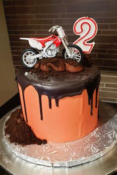 a birthday cake with a dirt bike and number two on top is sitting on a silver platter