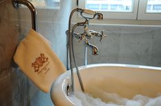 a bathtub filled with foam and water next to a towel hanging from the faucet