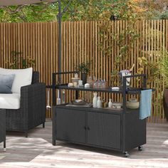 a patio with an umbrella and wicker furniture on the deck, in front of a bamboo fence