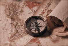 an old map with a compass and some tape on it, sitting next to a roll of toilet paper