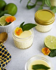 two jars filled with lemon curd next to limes and flowers