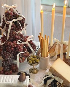 a table topped with bread and grapes next to candles