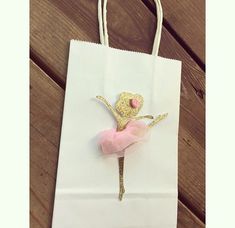 a white bag with a pink and gold ballerina on it sitting on a wooden floor