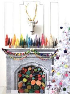 a decorated christmas tree in front of a fireplace with a deer head on the mantle