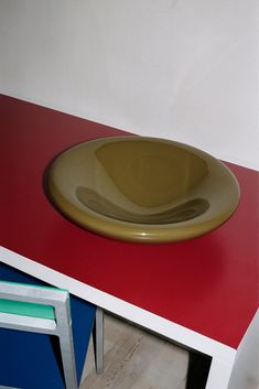 a yellow bowl sitting on top of a red counter next to a blue and white chair