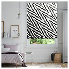 a bedroom with white walls and black and white patterned blind in the window sill