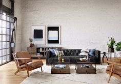 a living room filled with furniture next to a white brick wall and wooden flooring