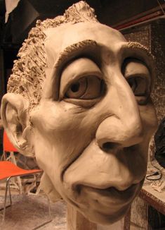 a clay sculpture of an old man's face is shown in front of a chair