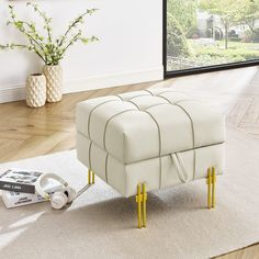 a white ottoman sitting on top of a hard wood floor next to a vase with flowers