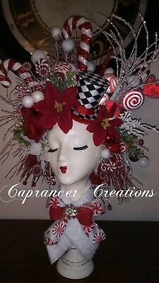 a white mannequin head with red flowers and candy canes