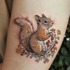 a small squirrel tattoo on the right side of the leg, with flowers and leaves around it