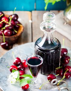 cherries on a plate next to a bottle of wine