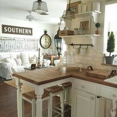 a kitchen with white cabinets and wooden counter tops next to a living room couches