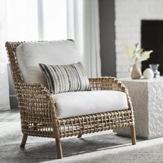 a wicker chair sitting in front of a fire place next to a white table