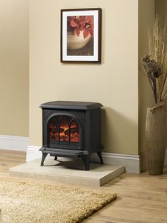 a wood burning stove sitting on top of a hard wood floor next to a vase