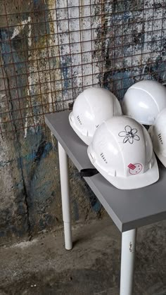 white hard hats sitting on top of a table in front of a grungy wall