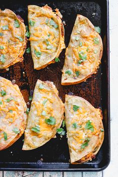 six cheesy flatbreads on a baking sheet with green garnish