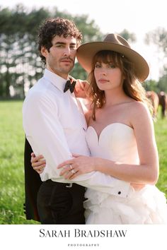 a bride and groom posing for a photo in the grass with horses behind them at their wedding