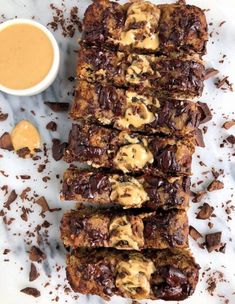 chocolate chip cookie bars with peanut butter on top and sauce in the middle next to them