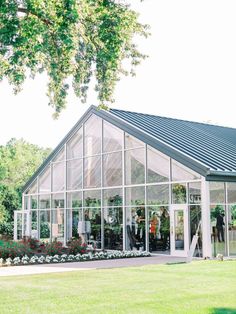 a large glass house sitting on top of a lush green field