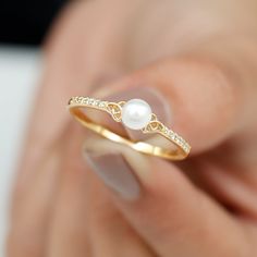 a woman's hand holding a gold ring with pearls and diamonds on the side