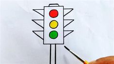 a person is drawing a traffic light with colored pencils on white paper and there is a marker in the foreground