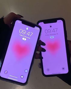 two people holding up their iphones in front of the screen with heart images on them