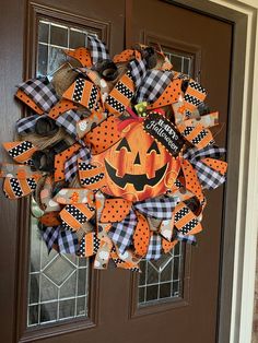 a halloween wreath with pumpkins and black and white checkered ribbon on the front door