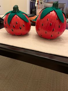 two red painted pumpkins sitting on top of a table