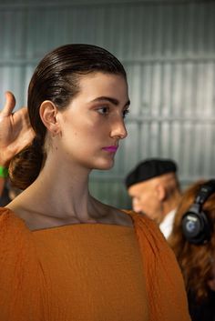 a woman in an orange top with headphones on