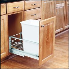 a kitchen with wooden cabinets and an open dishwasher drawer in the middle that is filled with food