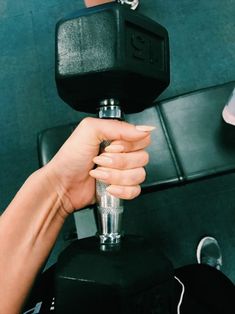 a hand holding a black object in front of a green wall