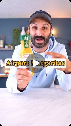 a man holding up a bottle of orange juice with the words airport i margaritas