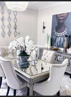 a dining room table with white chairs and flowers on it