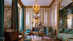 an ornately decorated living room with blue and gold furniture, chandelier and curtains