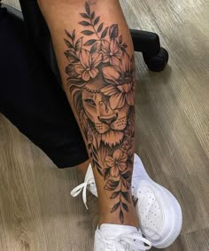 a woman's leg with a lion and flowers tattoo on her left calf area