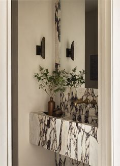 a bathroom with marble counter tops and two vases on the wall next to it