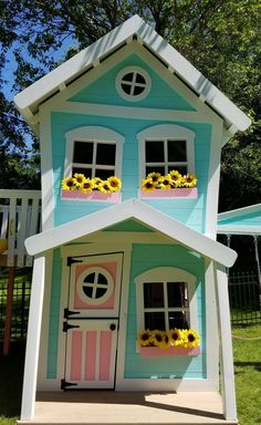 a blue and pink house with sunflowers in the windows on each window sill