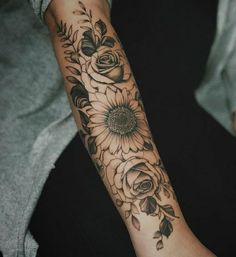 a woman's arm with flowers and leaves on it