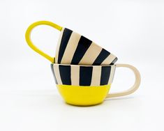 three striped cups sitting side by side on a white surface with one yellow cup in the middle