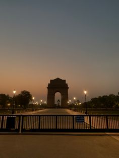 the gate is lit up at night with street lamps on either side and in front of it