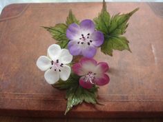 three purple and white flowers sitting on top of a brown suitcase