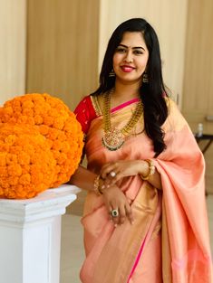 a woman standing in front of a large orange flower arrangement with her hands on her hips