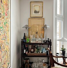 a shelf with bottles and glasses on top of it in a room next to a window